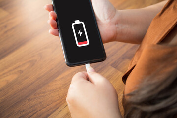 Close up a woman hands charging her mobile  phone on a wooden table