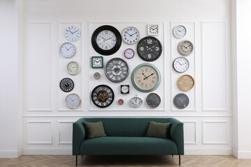 Wall Mural - Collection of different clocks and comfortable sofa in stylish room. Interior design