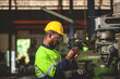 Portrait of an African-American technician or worker in an industrial setting. Wear a hard hat or helmet. eye protection glasses and a mechanical work vest in a heavy industrial plant