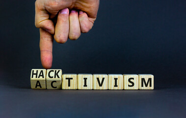 Activism or hacktivism symbol. Businessman turns wooden cubes and changes the word Activism to Hacktivism. Beautiful grey table grey background, copy space. Business activism hacktivism concept.