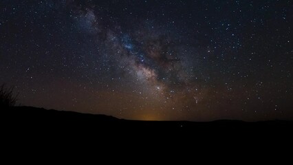 Colorful nebulas and stars make up the Milky Way as it crosses the sky as the Earth rotates - time lapse