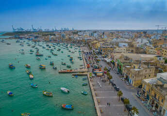 Sticker - Aerial panoramic view of Marsaxlokk - small, traditional fishing village in the South Eastern Region of Malta with many colorful fisherman boats in the bay