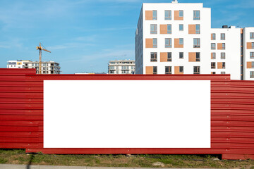 Wall Mural - Blank white advertising banner on the fence of construction site. Residential area with modern buildings on a sunny day.