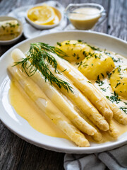 Wall Mural - White boiled asparagus in hollandaise sauce with potato puree served on wooden black table
