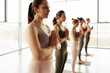 © Mediaphotos - Group of young yoga students standing in modern studio and making Namaste gesture while welcoming teacher