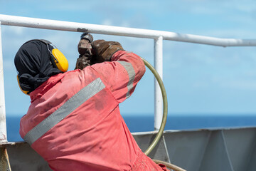 Wall Mural - Seaman ship crew working on deck derusting the vessel for painting.