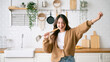 © Monster Ztudio - Asian young woman dancing in kitchen room. She happy and relaxing at free time on weekend