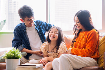 Wall Mural - cheerful asian family play tickle parent daughter laugh smiling fun happiness together on sofa in living room,relax casual family activity after packing stuff for home moving finish home moving ideas 