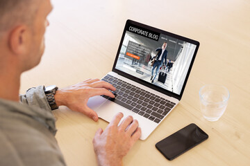 Man using laptop computer with sample corporate blog website on the screen.