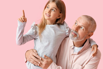 Canvas Print - Little girl pointing at something and her grandfather on pink background