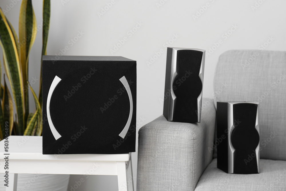Modern loudspeakers on stepladder stool and sofa in living room