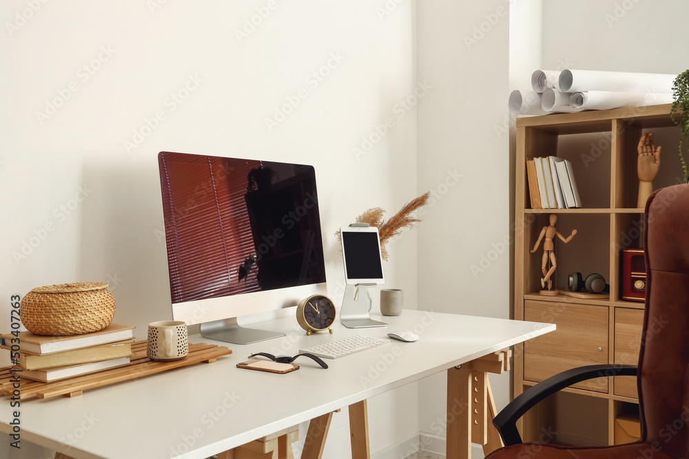 Workplace with modern gadgets near light wall