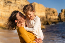 Smiling Woman Spending Leisure Time With Daughter At Beach On Sunny Day