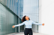 © Westend61 - Happy businesswoman with arms outstretched standing in front of office building