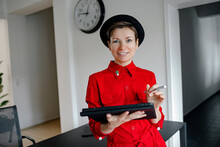 Smiling Businesswoman With Tablet PC Standing By Desk In Office