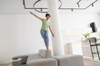© Westend61 - Smiling playful woman balancing on sofa at home