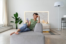 Woman Using Mobile Phone Sitting On Sofa At Home