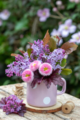 Blumenstrauß mit Maßliebchen und Flieder in vintage Emaille-Tasse