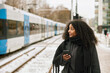 © Johnér - Woman at train station platform holding cell phone