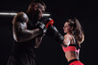 © andy_gin - Athletic woman in red shorts and top is boxing with a trainer. Boxing and mixed martial arts concept.