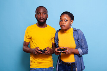 Poster - Boyfriend and girlfriend playing video games with controller on console. Modern couple holding joystick to play online game together, using accessories to have fun. Leisure activity