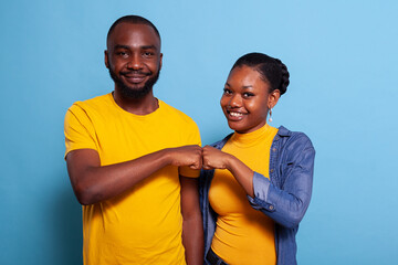 Portrait of smiling couple bumping fists together on camera, celebrating successful teamwork with agreement gesture. Girlfriend and boyfriend being partners and having achievement.