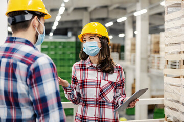 Wall Mural - A female food factory inspector with tablet talking to worker about export during corona virus.