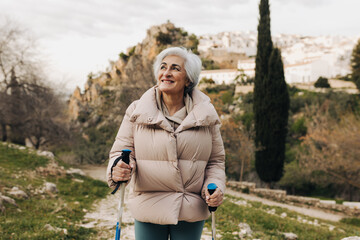 mature woman trekking with hiking poles outdoors