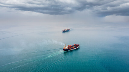 two container ship carrying container box global business delivery service cargo by freight shipping commercial trade logistic and transportation over sea worldwide rainstrom background aerial view.