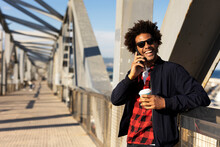 Smiling Black Man Holding Coffee To Go. Happy African Man Using The Phone Outside