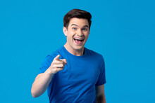 Smiling Handsome Young Caucasian Man Pointing Hand At You In Light Blue Isolated Background