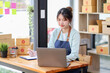 © David - Startup small business entrepreneur or freelance Asian woman using a laptop with box, Young success Asian woman with her hand lift up, online marketing packaging box and delivery, SME concept.