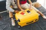 Fototapeta  - Young adult southeast asian couple hand place on luggage with passport for getting ready for holidays travel
