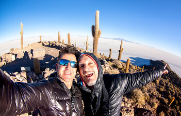 Adventurous best friends taking selfie at Salar De Uyuni in Bolivia - Travel life style enjoying happy fun moment - Trip together around world wonders - Bright filter with fisheye horizon distortion