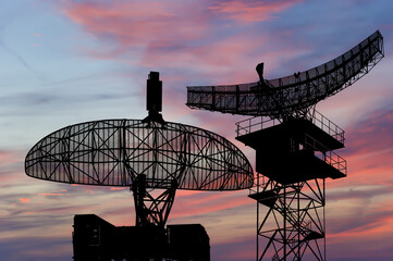 Wall Mural - Air defense radars of military mobile anti aircraft systems, modern army industry on the background of the sunset orange sky, Russia