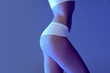 © Lustre Art Group  - Side view of cropped image of female body, bottocks in underwear isolated over blue studio background in neon, Anti-cellulite care.