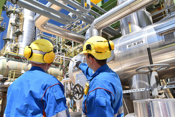 Wall Mural - group of industrial workers in a refinery - oil processing equipment and machinery