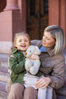 © LIGHTFIELD STUDIOS - joyful girl holding soft toy near mom on city street.