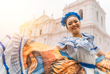 Nicaraguan Folklore Dancer Smiling And Looking At The Camera Outside The Cathedral Church In The Central Park Of The City Of Leon. The Woman Wears The Typical Dress Of Central America 