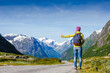 © olyphotostories - Hitchhiker hipster girl walking on road during holiday travel