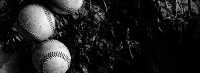 Wall Mural - Group of old vintage baseball balls on dark grunge background banner in black and white.