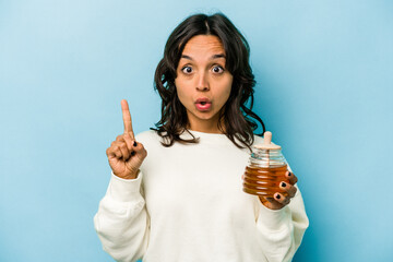 Wall Mural - Young hispanic woman holding a honey isolated on blue background having some great idea, concept of creativity.