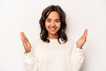 Poster - Young hispanic woman isolated on white background holding something little with forefingers, smiling and confident.