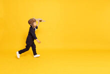 Asian Little Boy Running And Playing With Cardboard Airplane Isolated On Yellow Background