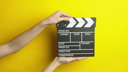 Wall Mural - Hand holding movie clapperboard on yellow background