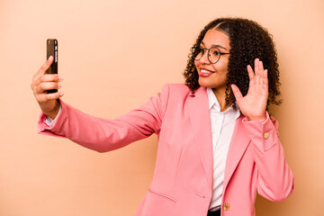 Young African American business woman holding mobile phone isolated on beige background