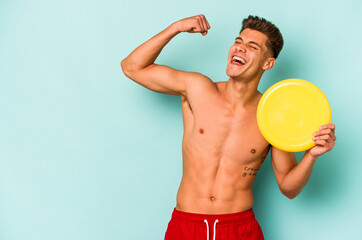 Young caucasian man playing with frisky isolated on blue background raising fist after a victory, winner concept.