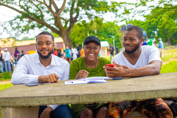 African friends sitting by the table in the campus park and studying