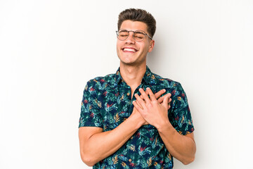 Young caucasian man isolated on white background has friendly expression, pressing palm to chest. Love concept.