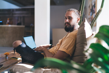 Portrait of bearded freelancer looking at camera during remote work at terrace - digital nomad lifestyle, Caucaisan hipster guy with modern netbook computer posing outdoors - technology communication